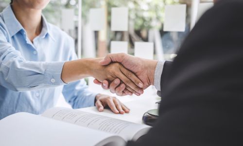 Händedruck über Dokumenten. MAV-Wahlen 2026 im Kontext von Arbeitsrecht und Zusammenarbeit.