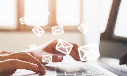 Hände tippen auf Laptop, E-Mail-Symbole schweben. MAV-Wahlen 2026.