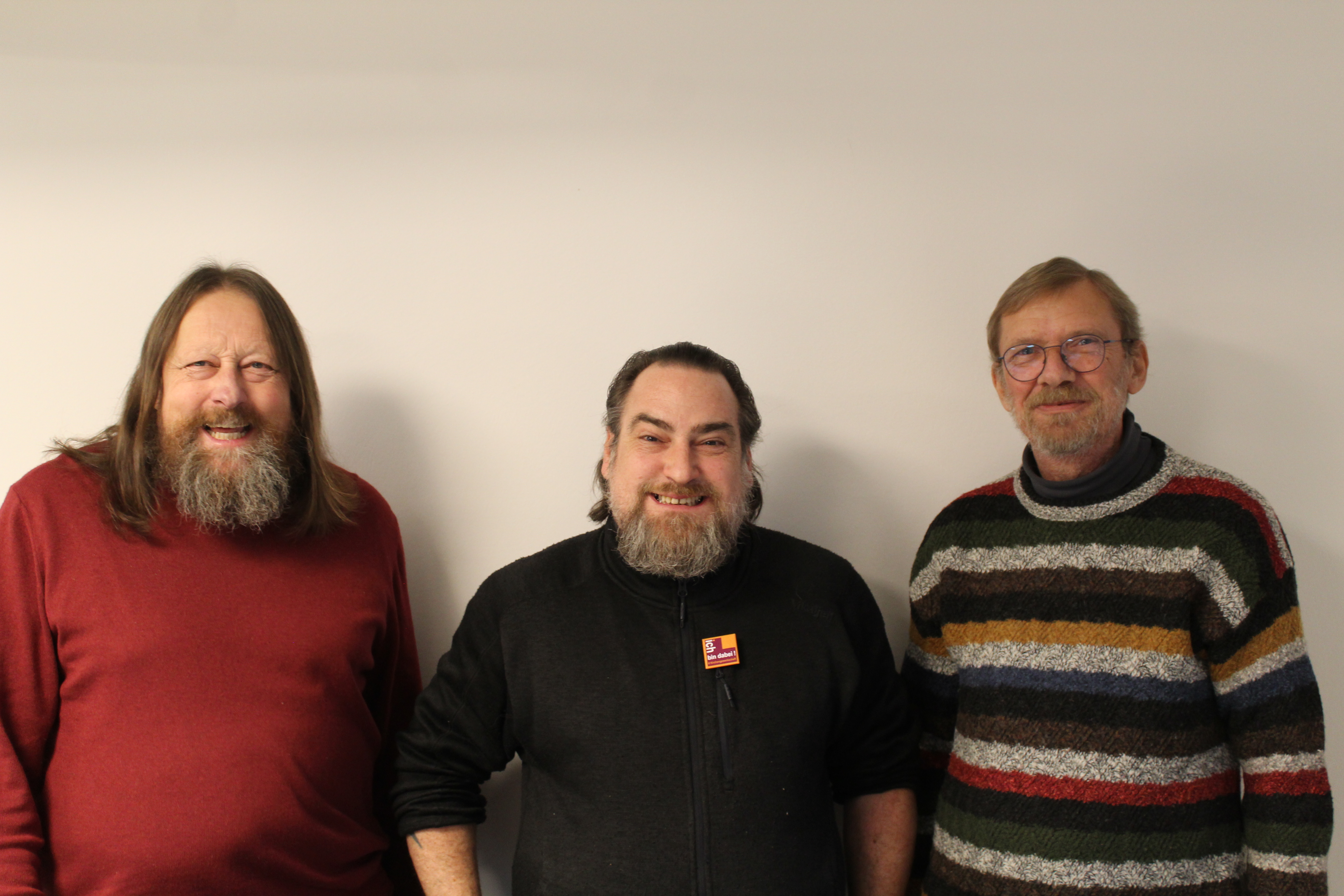 Drei Männer, wahrscheinlich Mitglieder der Kirchengewerkschaft Hessen, lächeln in die Kamera.