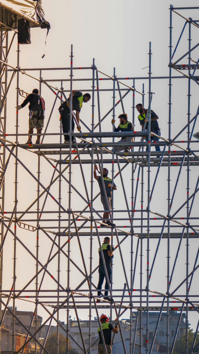 Construction workers on scaffolding at a building site, demonstrating cooperation and safety.