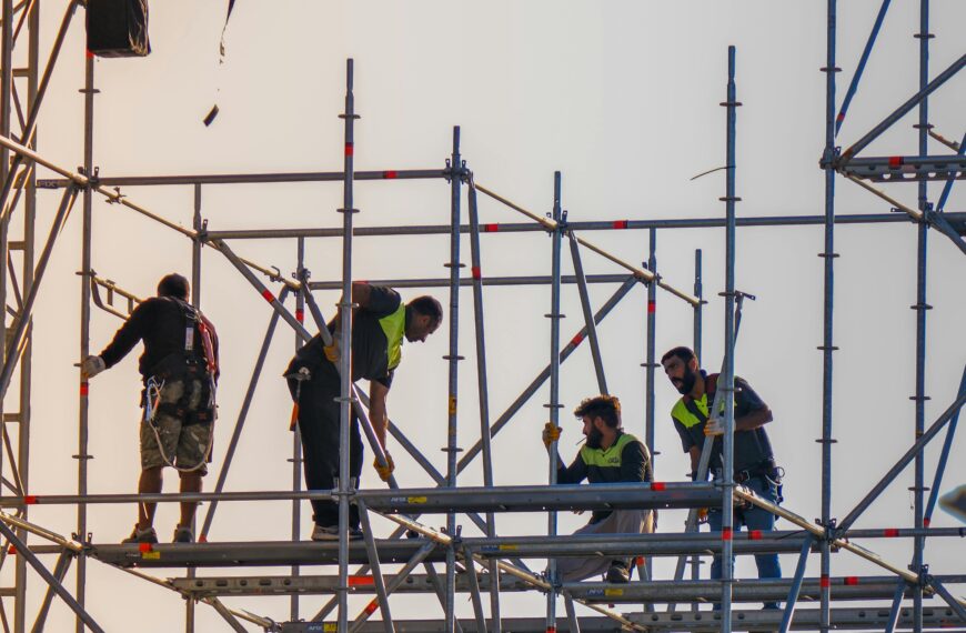 Construction workers on scaffolding at a building site, demonstrating cooperation and safety.