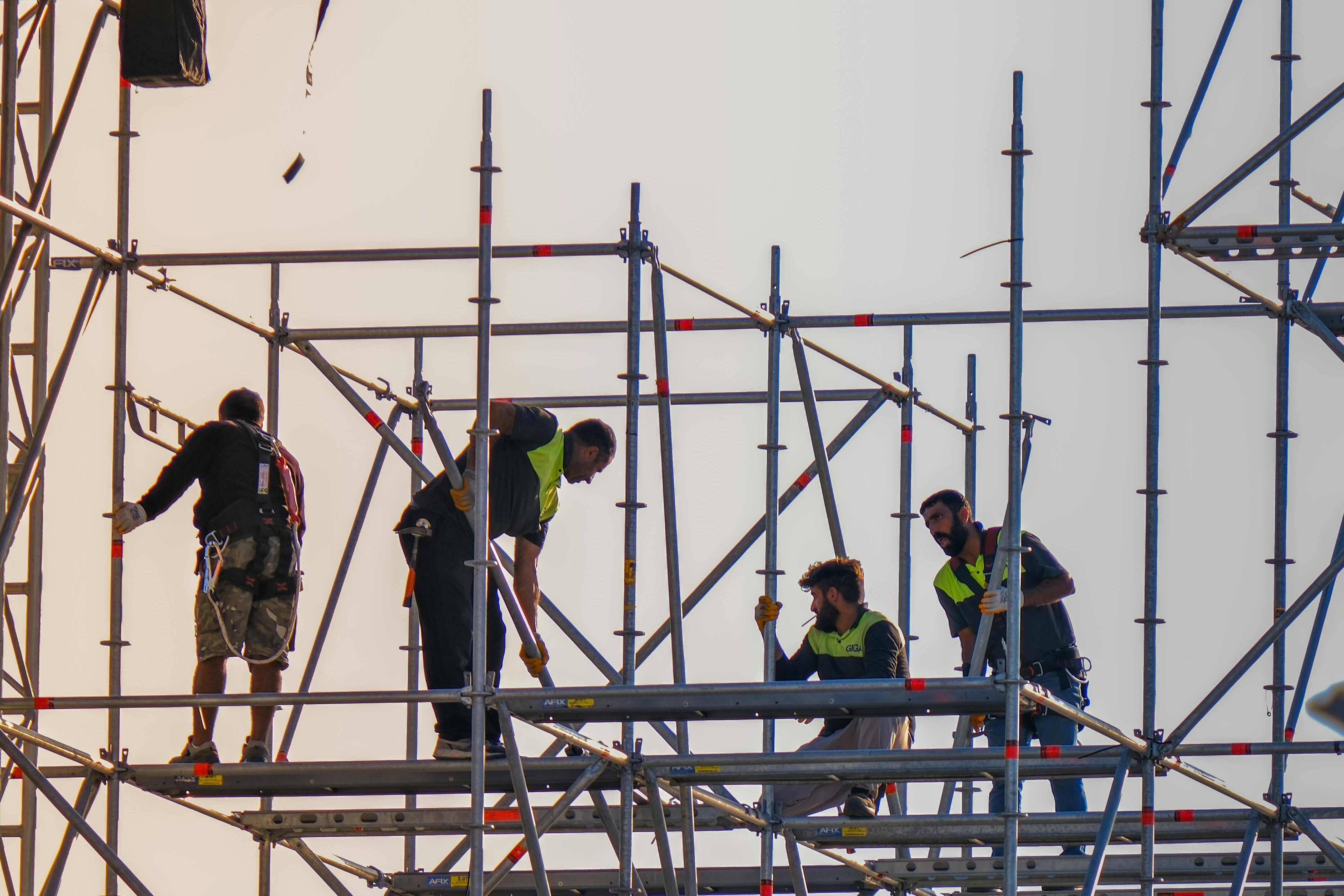 Construction workers on scaffolding at a building site, demonstrating cooperation and safety.