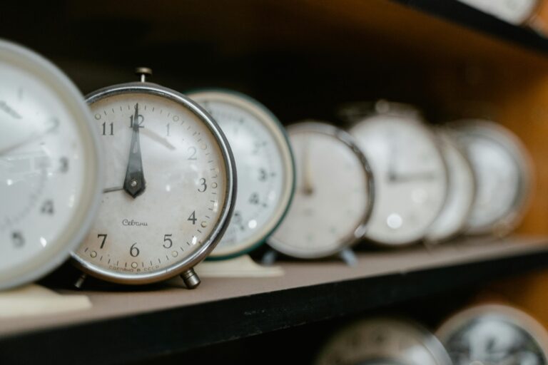 A collection of vintage analogue alarm clocks arranged on a wooden shelf.