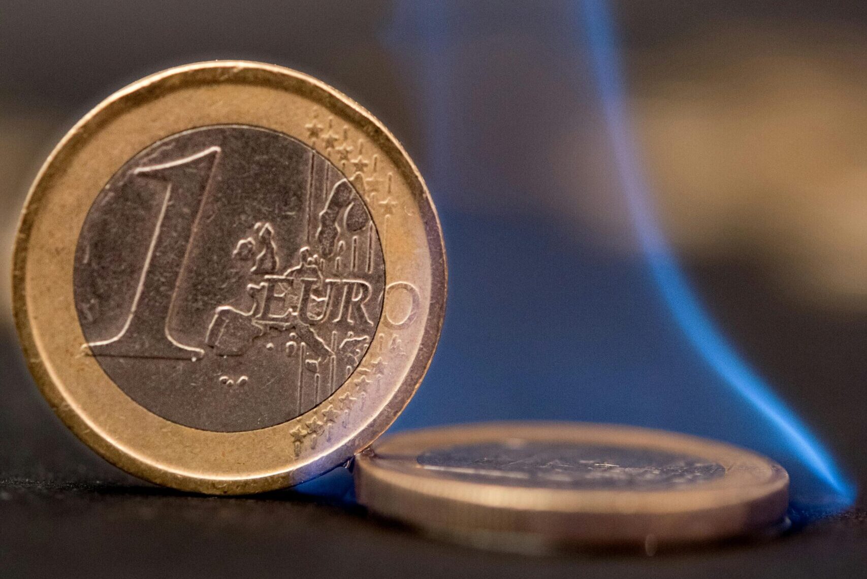 Burning euro coins with blue flames representing financial risk or crisis.