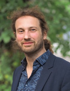 Mann mit lockigem Haar und Bart im Sakko