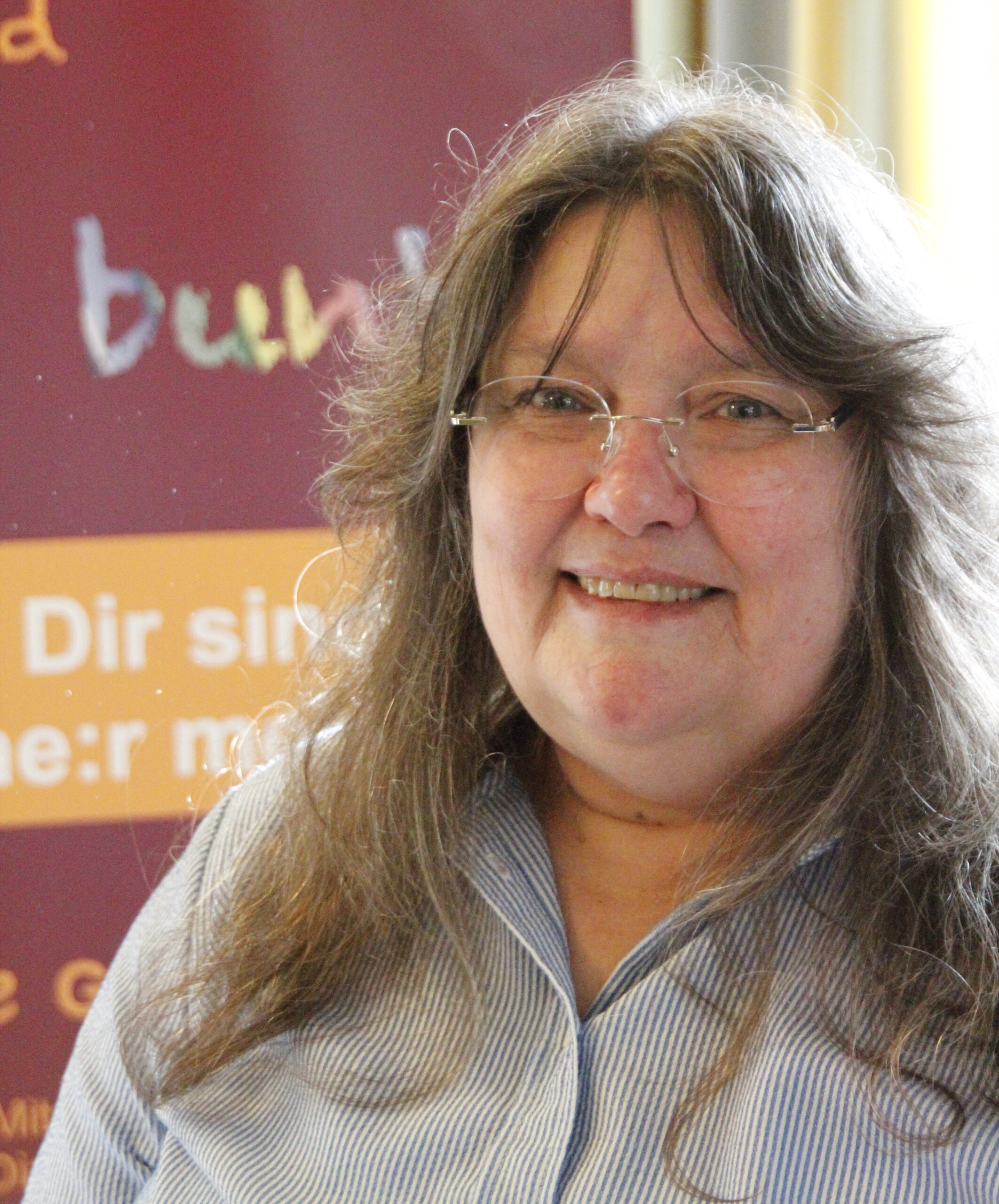 Frau mit Brille und langen Haaren lächelt vor Banner mit Schriftzug "bund