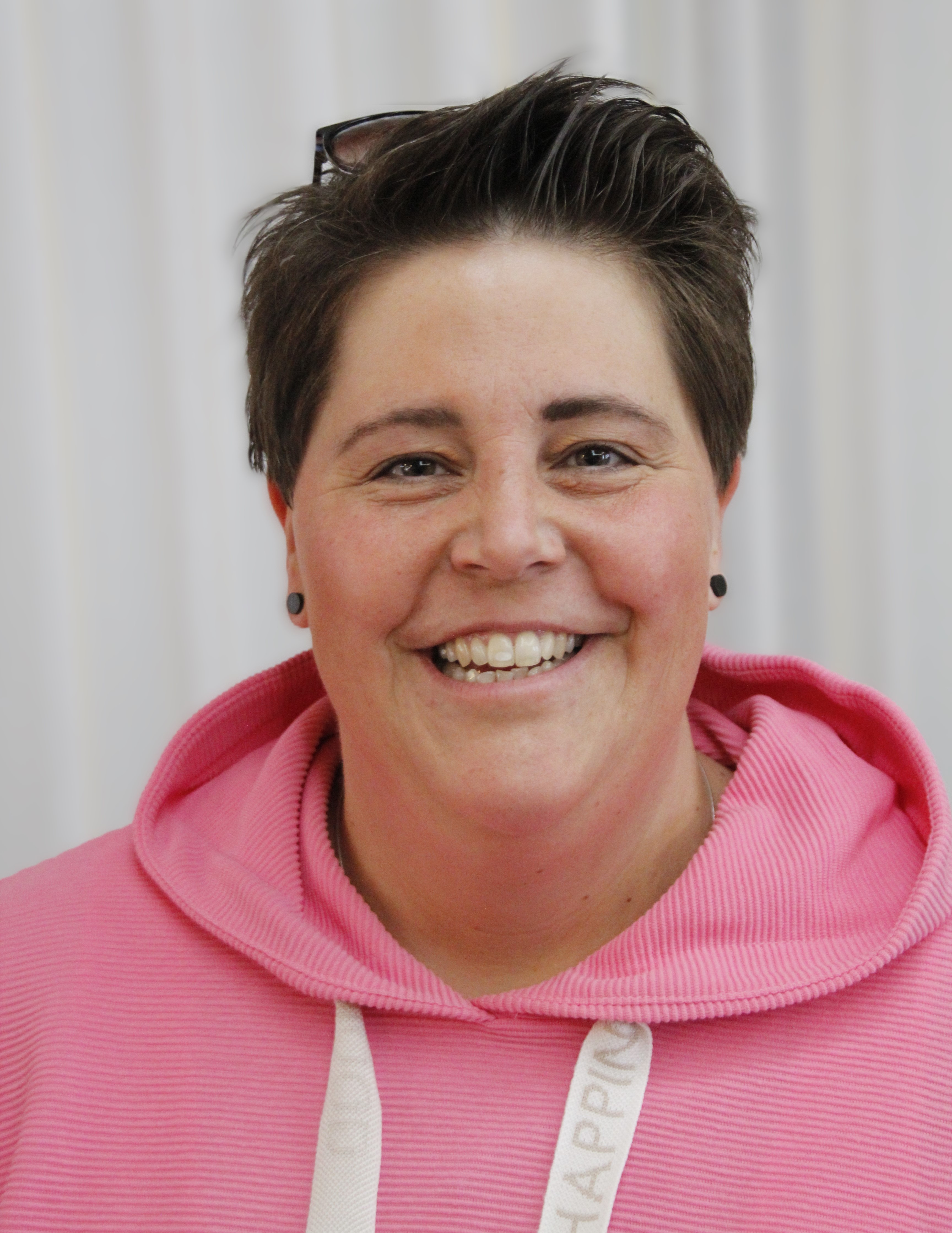 Frau mit kurzem Haar und pinkem Hoodie lächelt